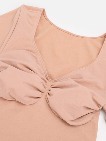 Close-up of a beige-colored top with a scrunched detail on a white background