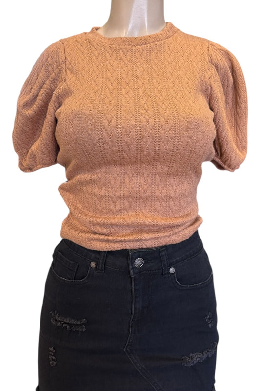 Mannequin wearing a tan knit top and black jeans on a white background